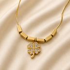 Collar dorado cola de ratón con dije de trébol de zirconias sobre satén color hueso